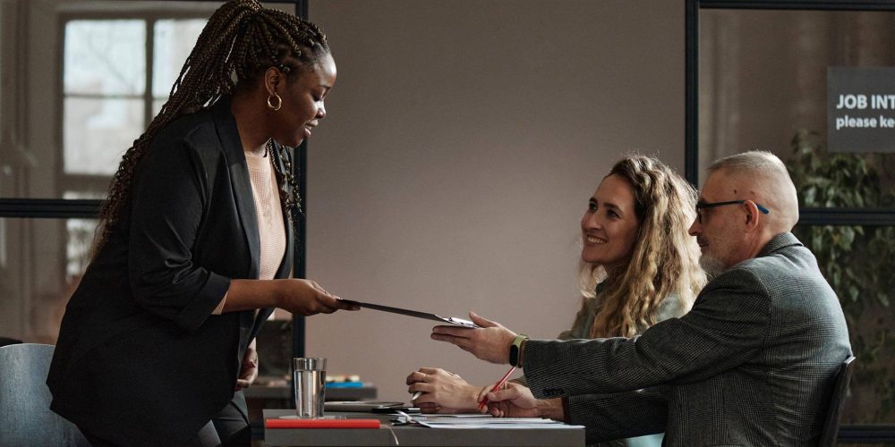 woman-giving-her-resume-to-interviewer-TCTJC8J